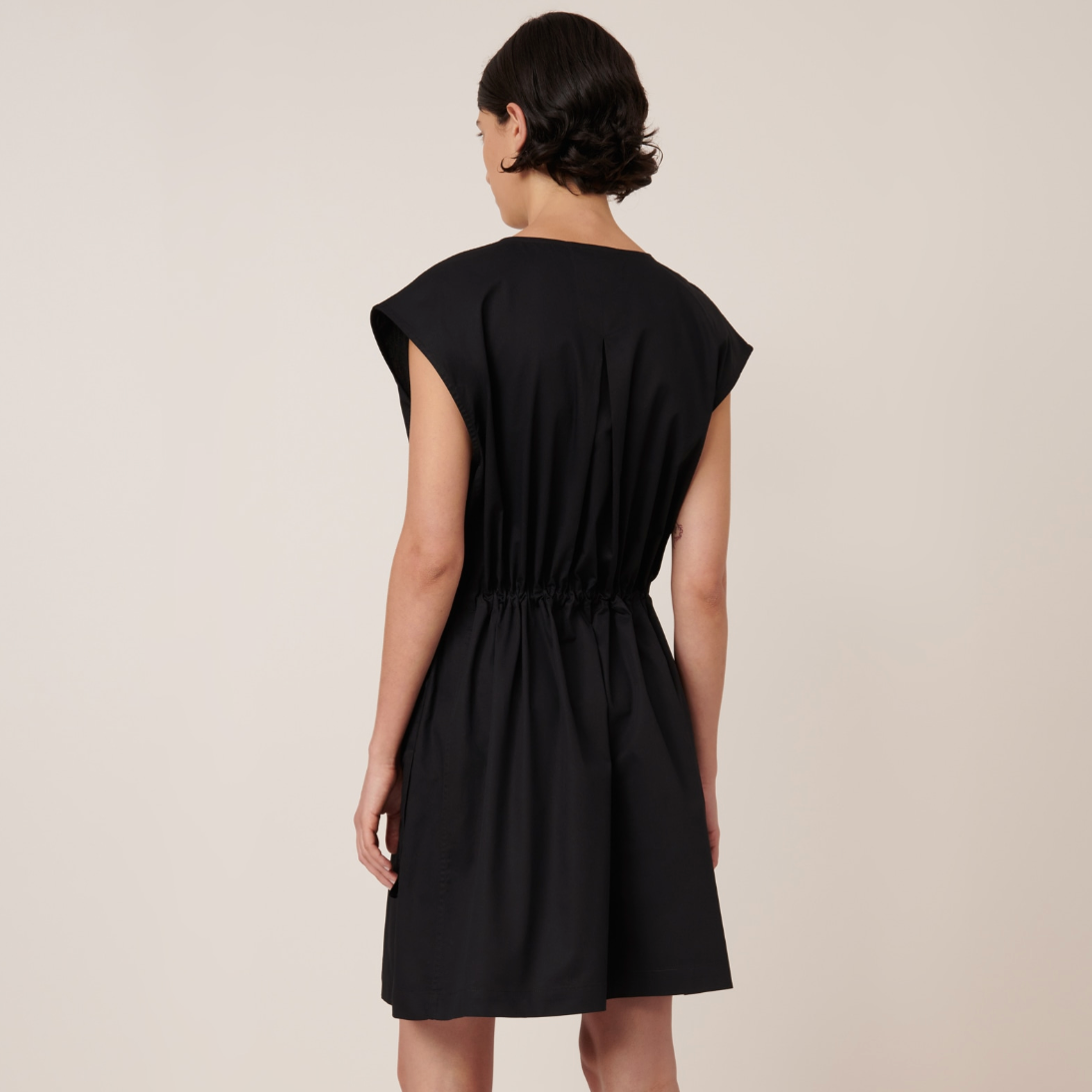 Woman wearing a black dress against a beige background