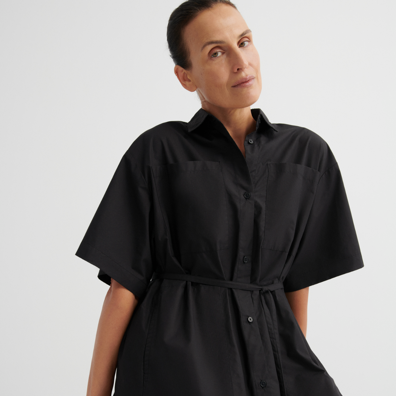 Woman wearing a black shirt dress against a plain background