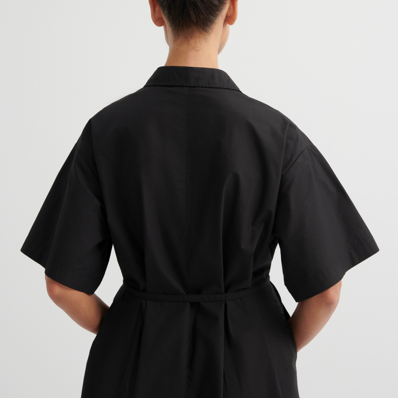 Person wearing a black dress with a plain background