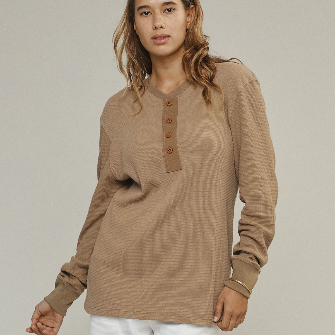Woman wearing a brown long-sleeve shirt with buttons on a plain background