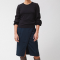 Person wearing a black sweater and navy skirt on a white background