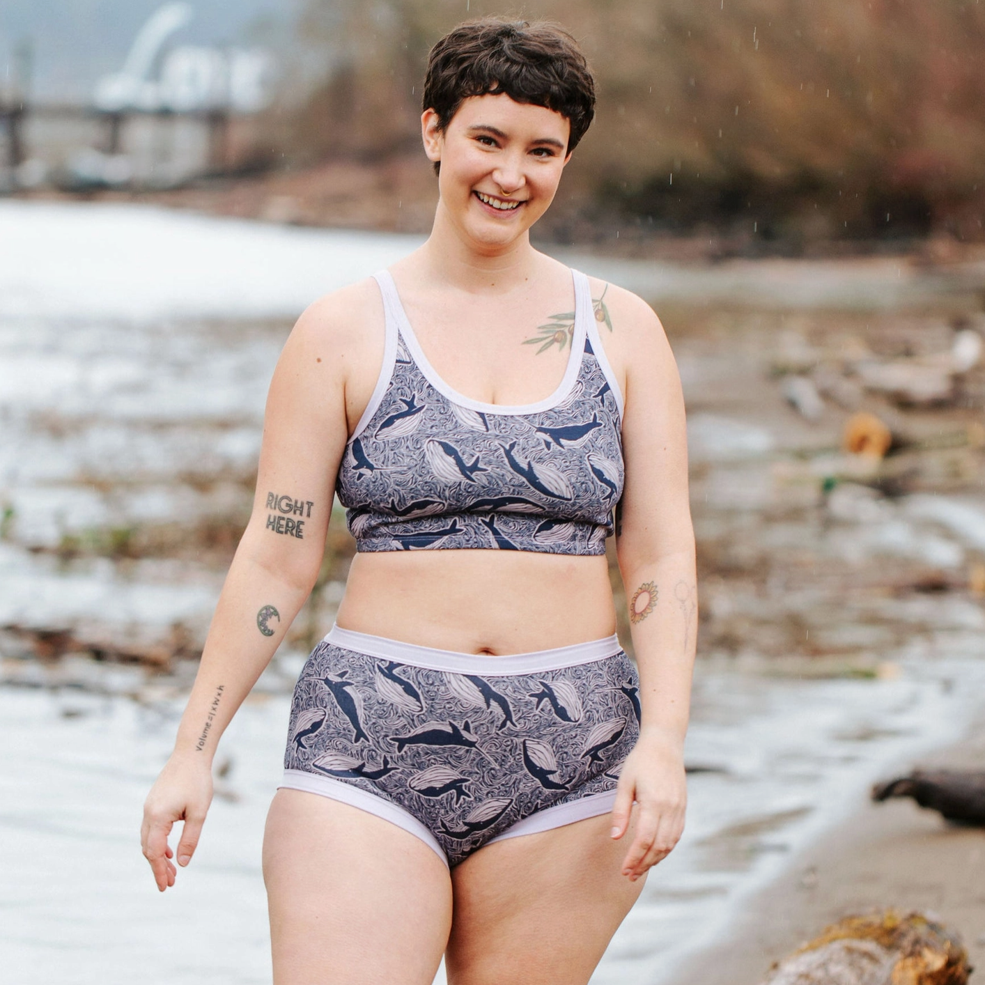 Person wearing a patterned bra and underwear set standing on a beach.