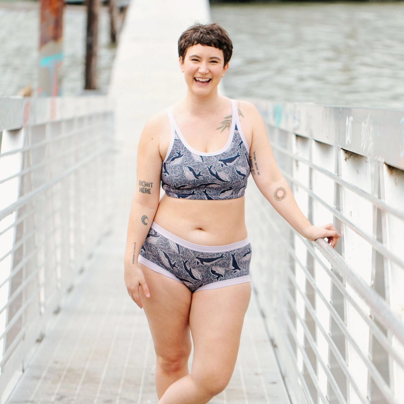 Woman wearing a patterned underwear set standing on a wooden bridge.