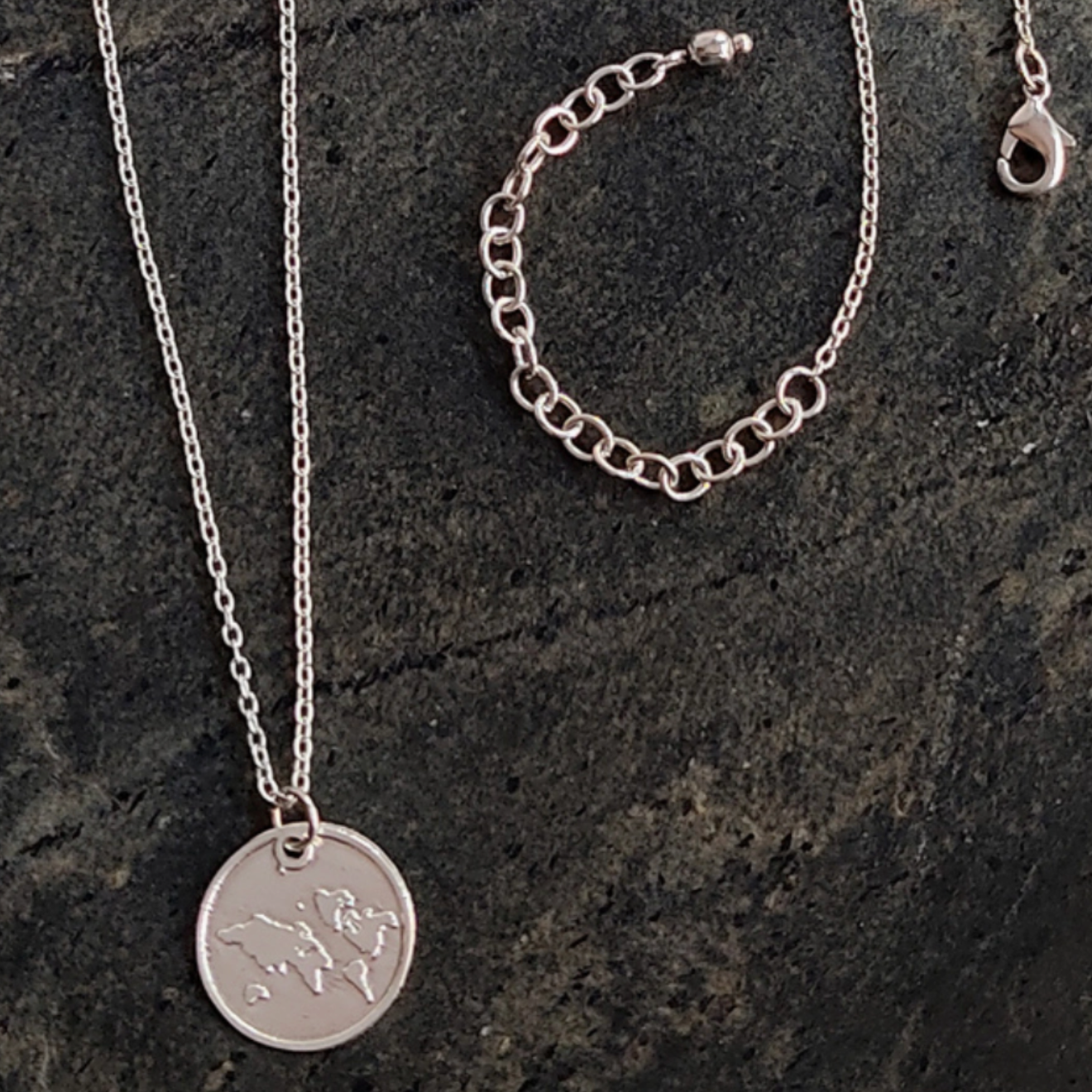 Silver necklace with a round pendant on a dark stone surface