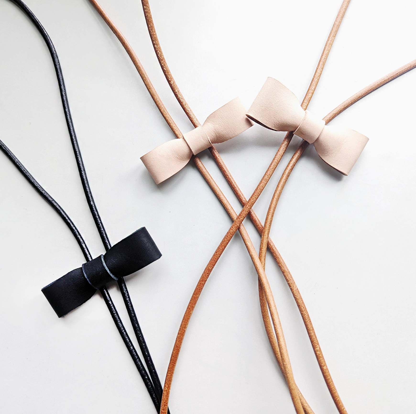 Black and beige leather straps with bows on a light gray background