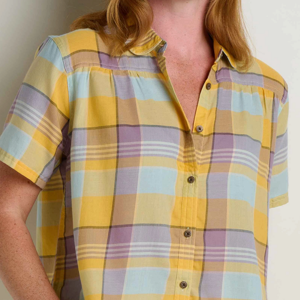 Woman wearing a yellow and purple plaid shirt against a plain background