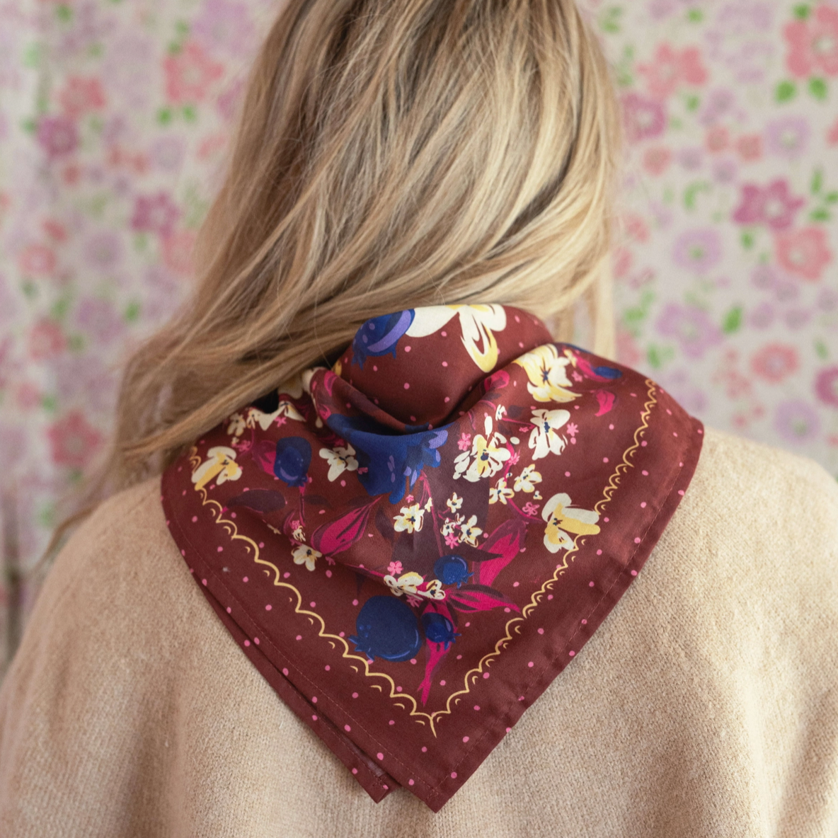 Person wearing a floral headscarf with a patterned background
