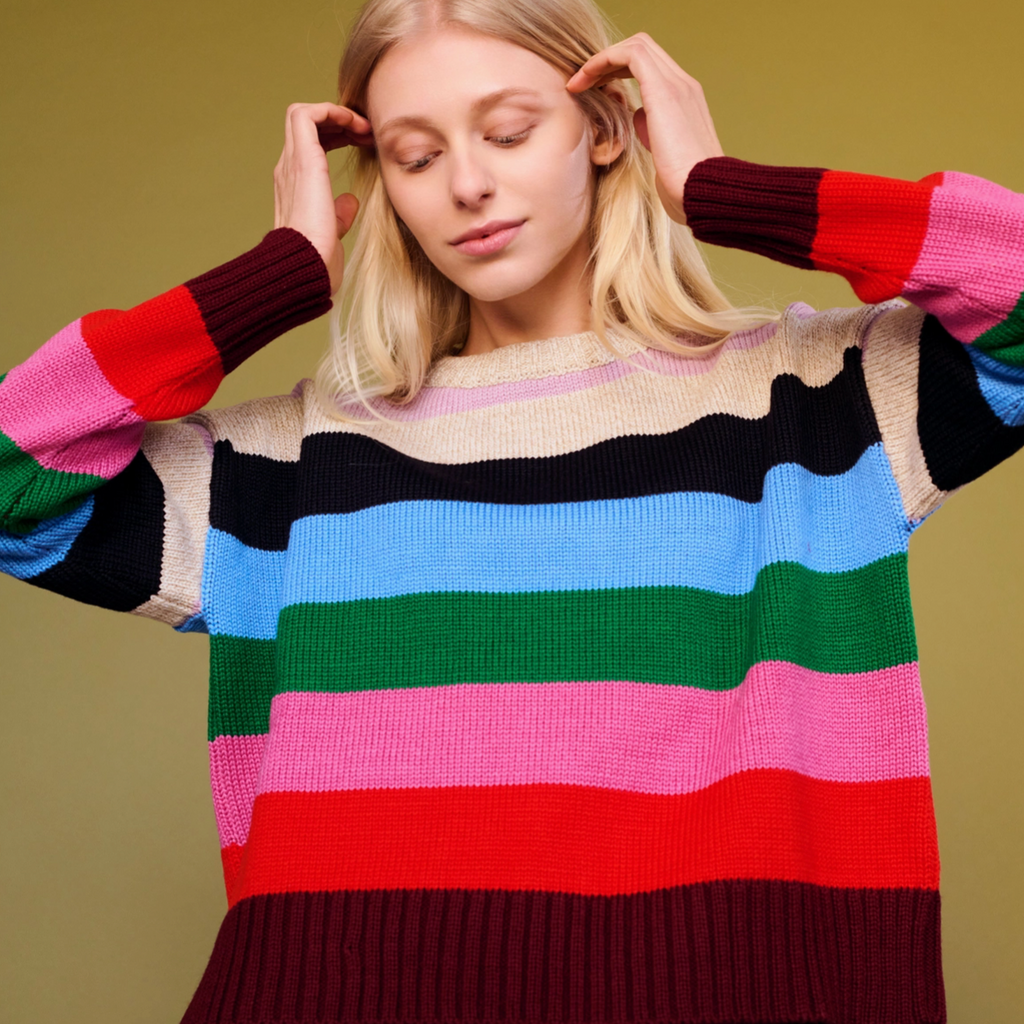 Woman wearing a colorful striped sweater against a solid background