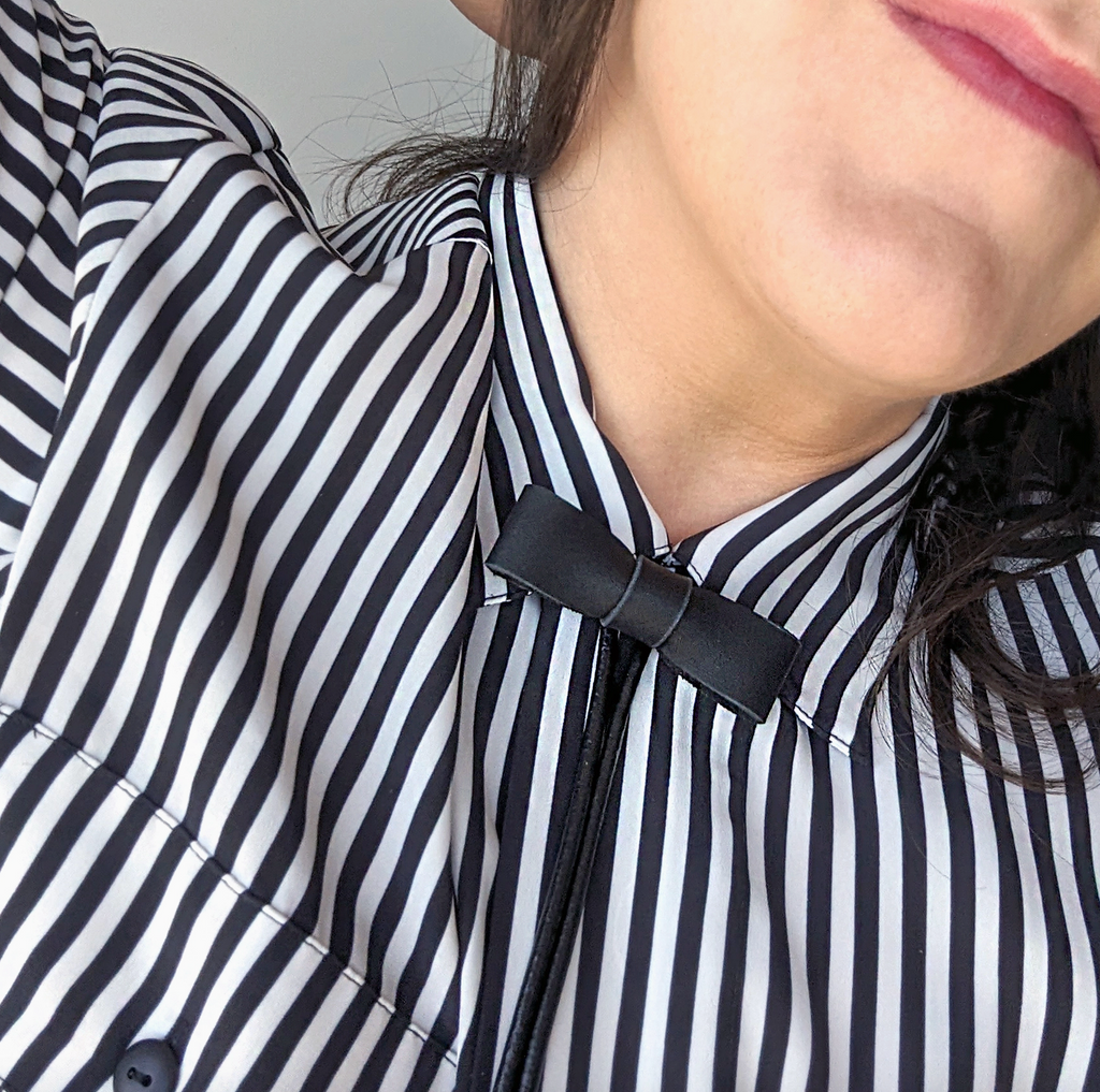 Close-up of a person wearing a black and white striped shirt with a bow tie.